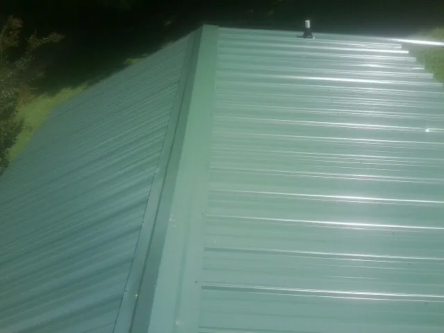 New green metal panels meeting at the ridge of a roof — Flat Roof Repair work by our crew in Old Bethpage