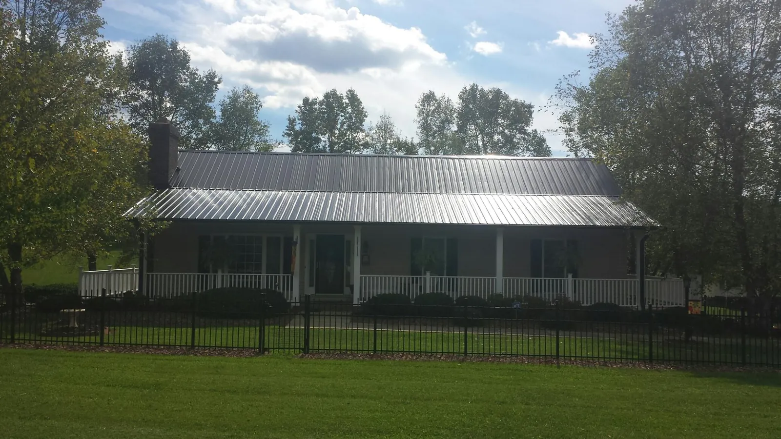 Gray metal roof on a brick ranch with a full width front porch — Gutter Guard Installation work by our crew in Old Bethpage