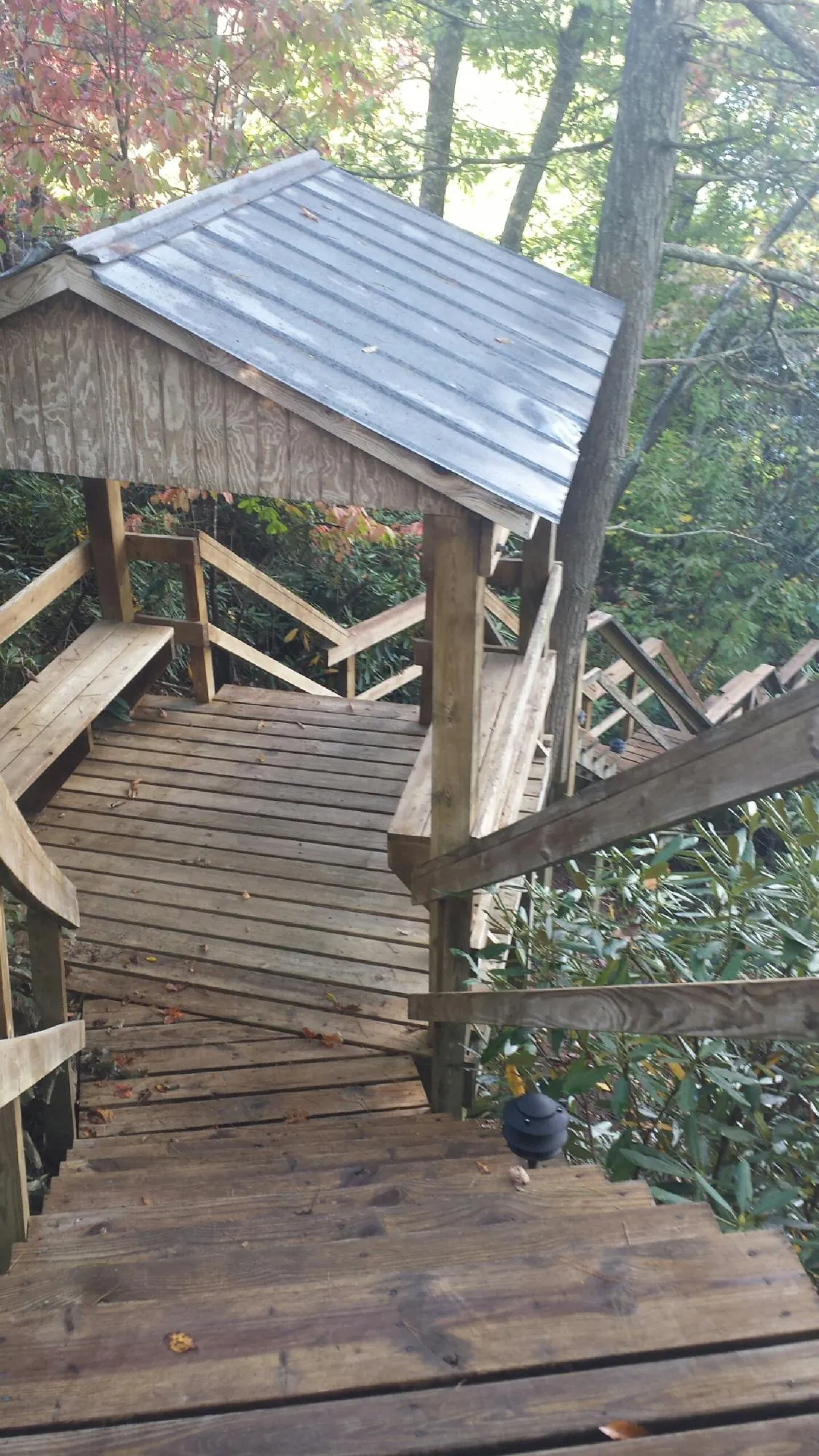 Metal roofed shelter over wooden steps on a wooded walkway — Skylight Repair & Installation work by our crew in Old Bethpage